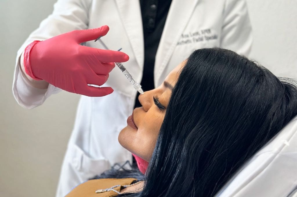 Specialist Wearing White Coat And Pink Gloves Applying Juvederm Filler Facial Treatment On Woman Face