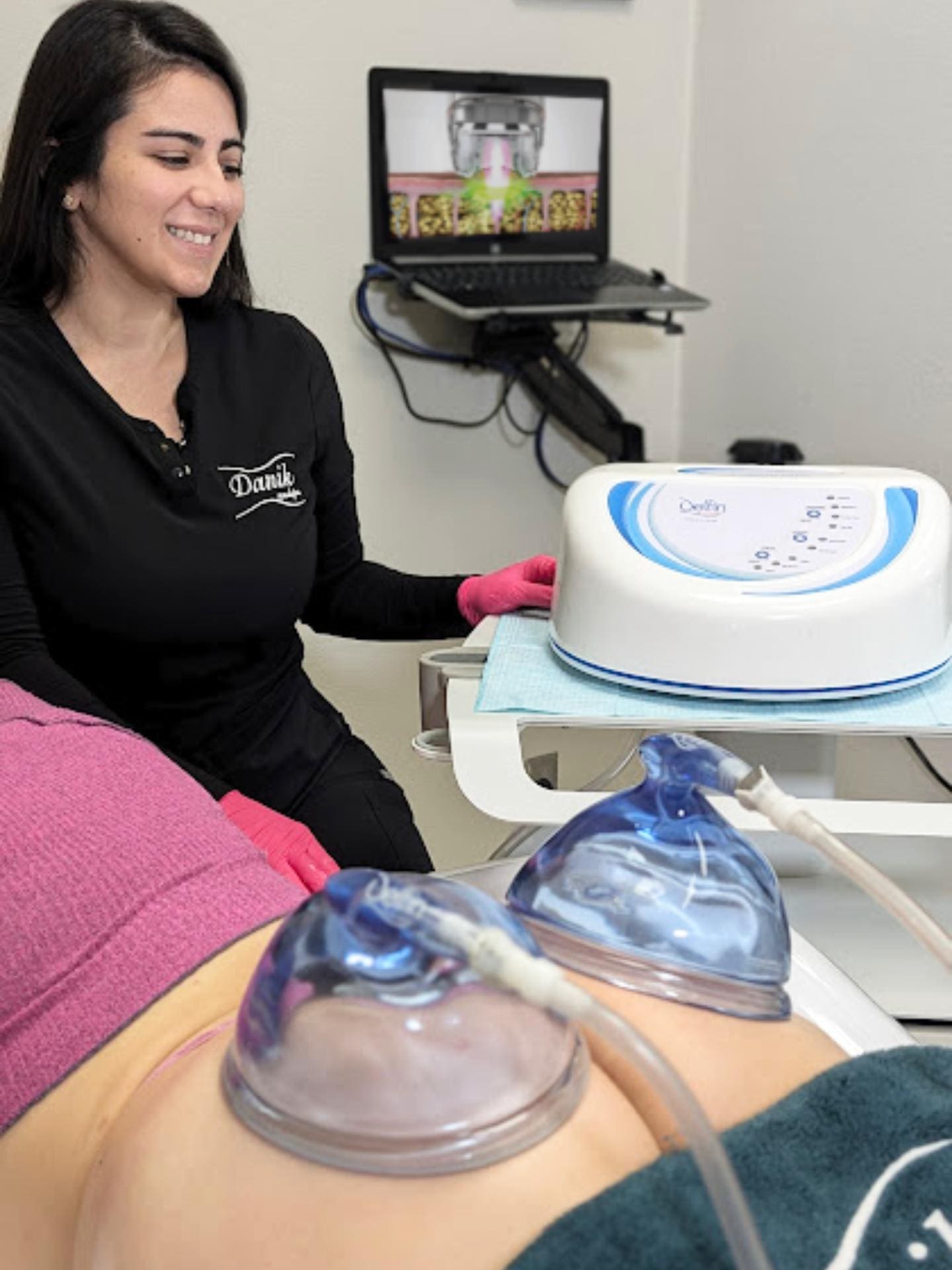 Specialist Wearing Black Uniform And Pink Gloves Applies Vaccum Therapy On Glutes To A Woman Lying Face Down