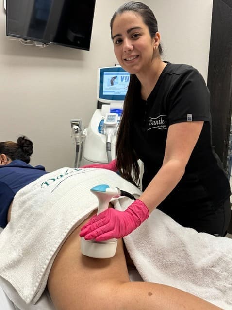 Specialist using ultrasound cavitation device on a client’s abdomen.